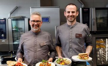 Thomas Mindrup (l. im Bild) und Markus Sandfort (r. im Bild) vom EAT-Team präsentieren die KI-gerierten Gerichte Ägyptischer Koshari, das Piri-Piri Hühnchen, die Quinoa-Bowl und den Hawaii-Burger. Sie stehen im April auf dem Speiseplan im EAT.